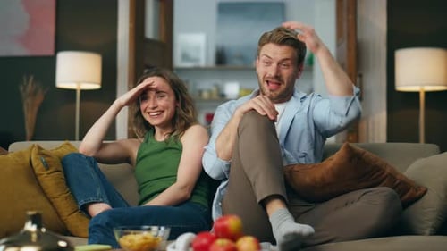 Laughing Pair Watching Comedy Sitting Home Couch. Overjoyed Couple Enjoying Exciting Tv Show In E...