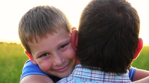 Affectionate Boy Hugging a Man at Sunset