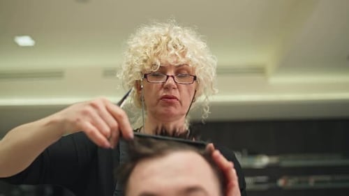 Stylish Hairdresser Giving Haircut to Man Indoors