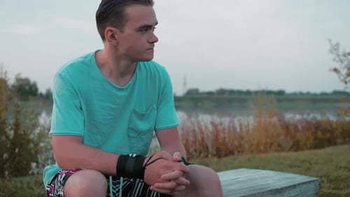 Young Man Smiling While Sitting near Lake