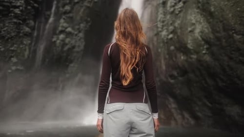 Woman Opening Arms Enjoying Waterfall in Tropical Rainforest Jungle