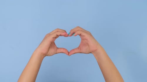 Hands Forming Heart Shape on Blue Background