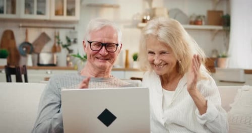 Happy Senior Couple Video Calling on Laptop at Home