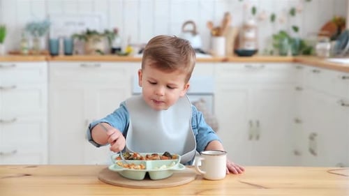Child Eating Food with Fork in Kitchen