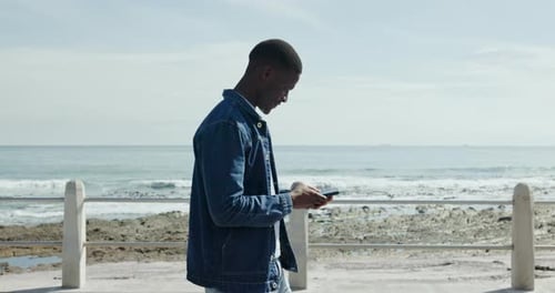 Phone, walking and black man at promenade for travel, vacation and typing text on holiday outdoor