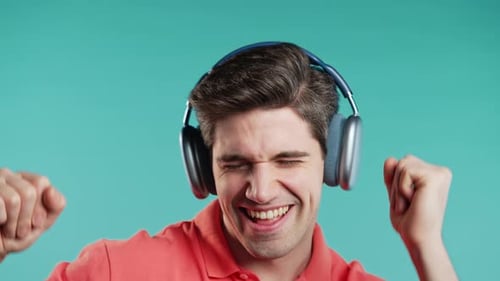Young Positive Man Listening Music Enjoying with Headphones Blue Studio