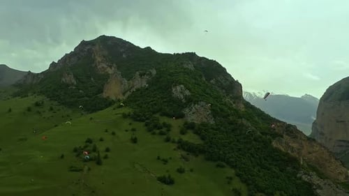 Many Paragliders in the Air Near a Mountain