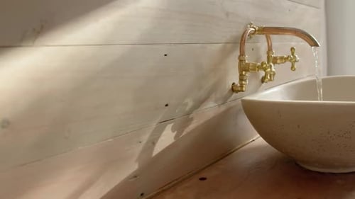 Close up of washbasin with running water in bathroom, slow motion