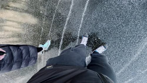 Aerial view of couple ice skating outdoors on frozen lake