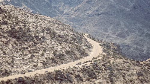 Scenic Winding Dirt Road Through Rocky Mountainous Terrain in Daylight