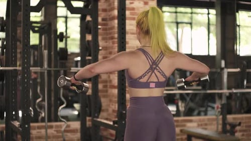 Gorgeous Female Professional Bodybuilder Doing Workout Exercises in Gym