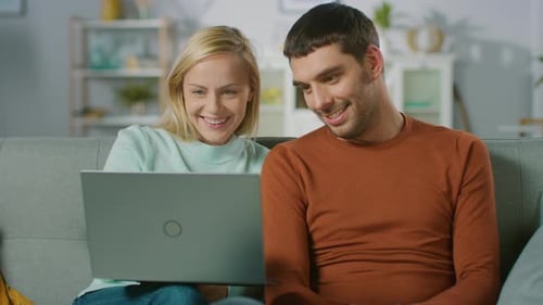 Smiling Couple Using Laptop Together on Couch