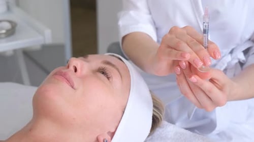 Botox Therapy Process A Beautician Holds a Needle Before Injecting Botox on Beautiful Woman's Face