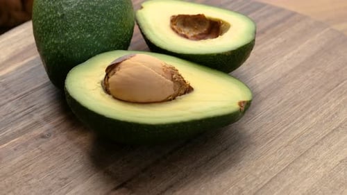 Vue rapprochée d'un avocat entier et demi tournant sur une surface en bois