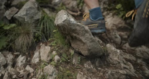 Close up of hikers feet walking up a hill, summer clothing, using hiking poles, wearing hiking shoes