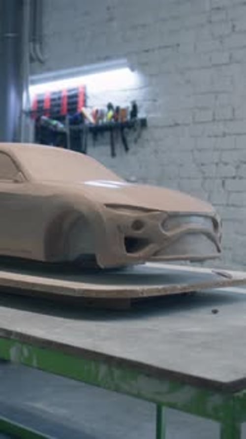 Sculpture inachevée d'un prototype de voiture posé sur une table en bois avec des outils de pose