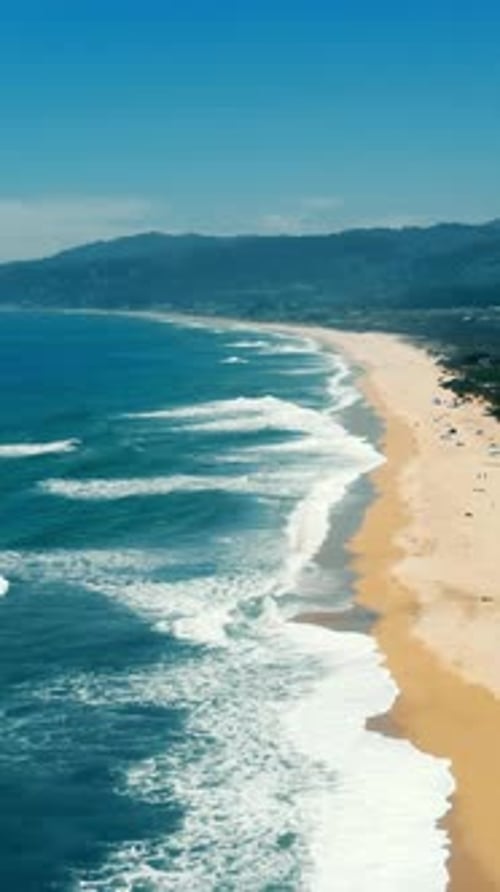 Aerial View of the Pacific Coastline in California Showing Golden Sandy Beach and Gentle Sea Waves