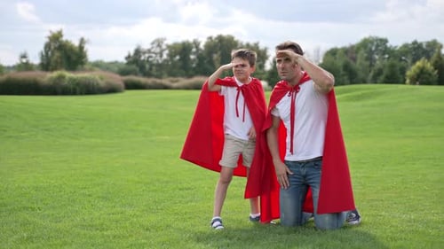 Father and Son Playing Superheroes in Park