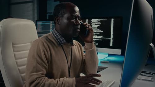 Man Working on Computer and Talking on Phone