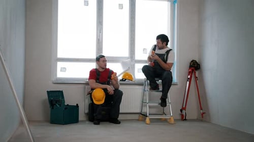 Apartment Repair in Draft Apartment Men Workers Having a Break