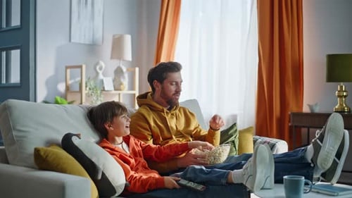 Father and Son Relaxing on Couch with Popcorn