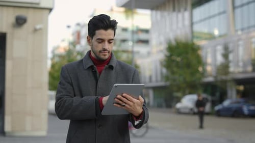 Jeune homme d'affaires multiethnique debout à l'extérieur en ville utilisant une tablette naviguant en ligne avec Handsome
