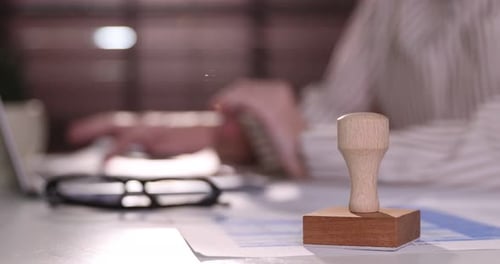 Femme travaillant avec un ordinateur portable au bureau à l'intérieur, focus sur un tampon en bois