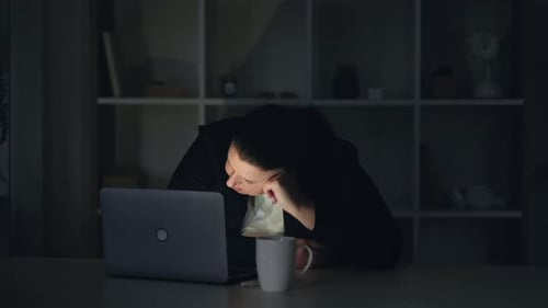 Young Adult Asleep at Laptop in Dark Home Office