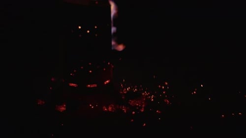 Flammenwerfer entzündet Flammen in einer Feuerstelle mit verstreuter Glut auf dem Boden