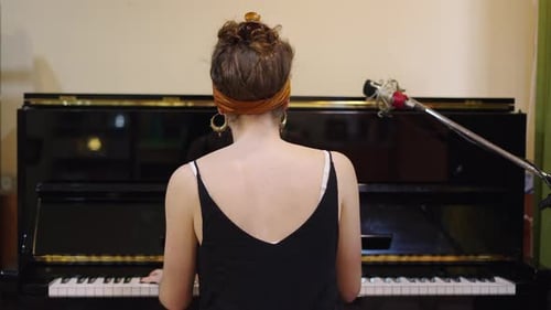 Woman Plays Piano in Indoor Setting