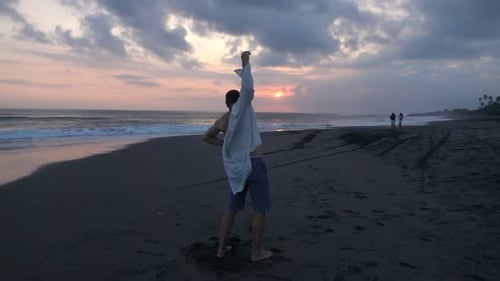 Man puts on shirt at sunset in super slow motion on a beautiful beach
