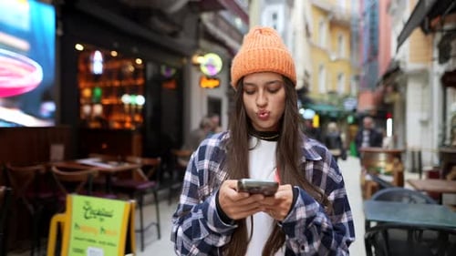 Young Woman Using Smartphone on Vibrant City Street
