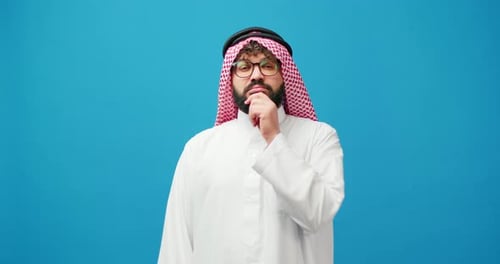 Man in traditional dress looking thoughtful, blue screen
