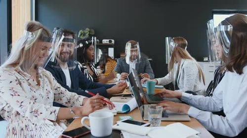 Team Collaborating at Table Wearing Face Shields