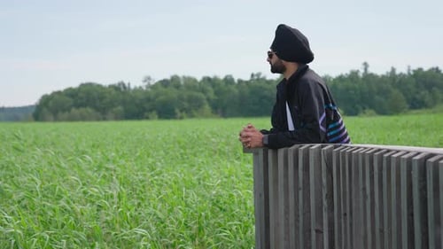 Indian Man In Sunglasses Looking At The Field With Green Crops. - wide