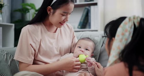 Infant with Two Women Playing with Toy at Home