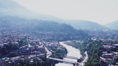 Une vue aérienne de la ville de Muzaffarabad nichée entre les montagnes. Une rivière sinueuse traverse la ville