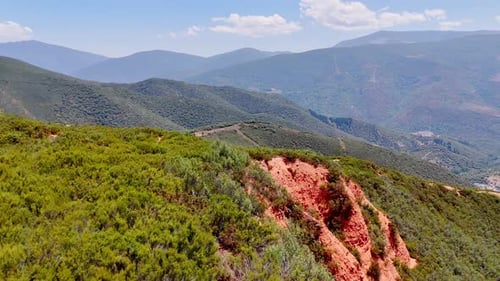 Flight above the mountainous landscape covered with green bushes and grass.