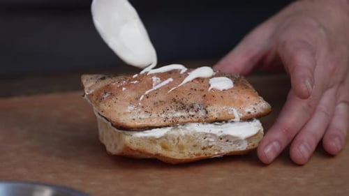 Chef Adding Mayonnaise On Top Of Sandwich Sprinkled With Pepper. close up