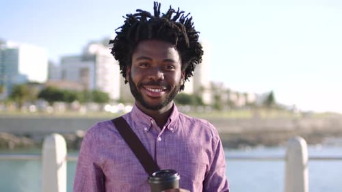 Portrait of trendy black man taking daily commute, having coffee and enjoying view of the city