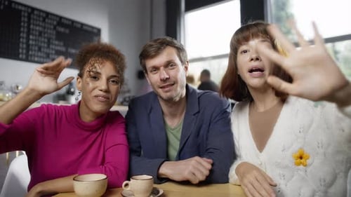 Multiracial Group of People Waving Goodbye to a Computer Webcam in a Coffee Shop