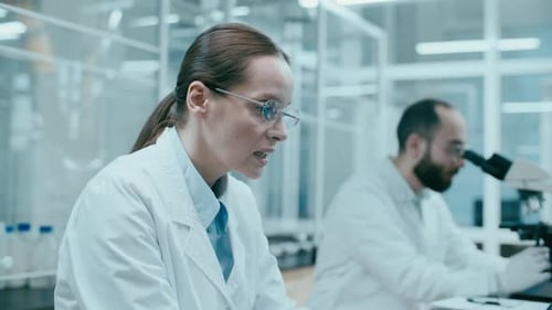 Scientists Working with Microscope and Laptop in Laboratory