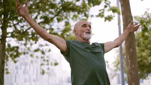 Man With Arms Outstretched in City Park