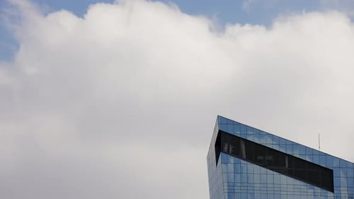Time lapse of the clouds forming and passing over a huge skyscraper building on the downtown comerci