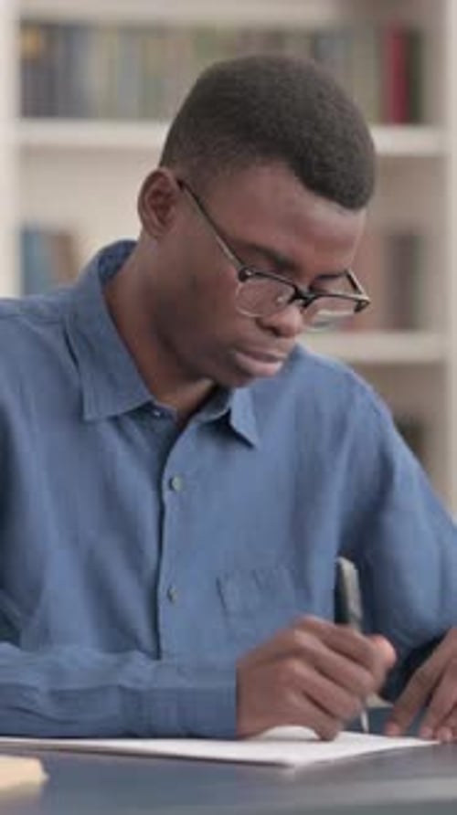 Young African Man Writing on Paper in Office, Vertical Video