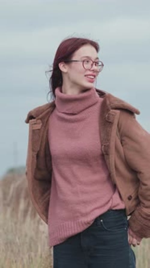 Young Woman Talking in Rural Field with Cloudy Sky
