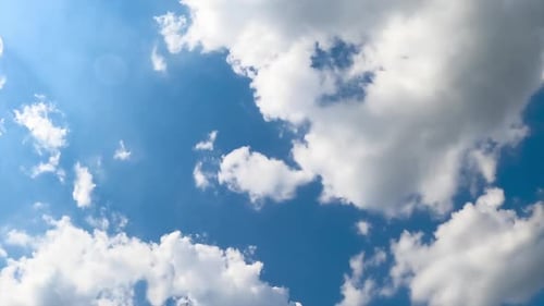 Nuages doux en coton volant dans le ciel azuré. Un soleil éclatant illumine les nuages. Vue à angle réduit