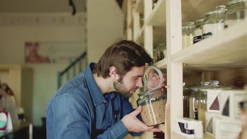 Young bearded shop assistant smelling organic products in a zero waste store
