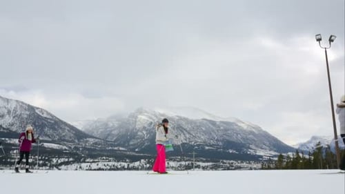 Family Crosscountry Skiing Snowy Field Below Mountains Bonding