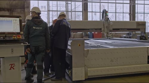 Workers Inspect Industrial Cutting Machine in Factory
